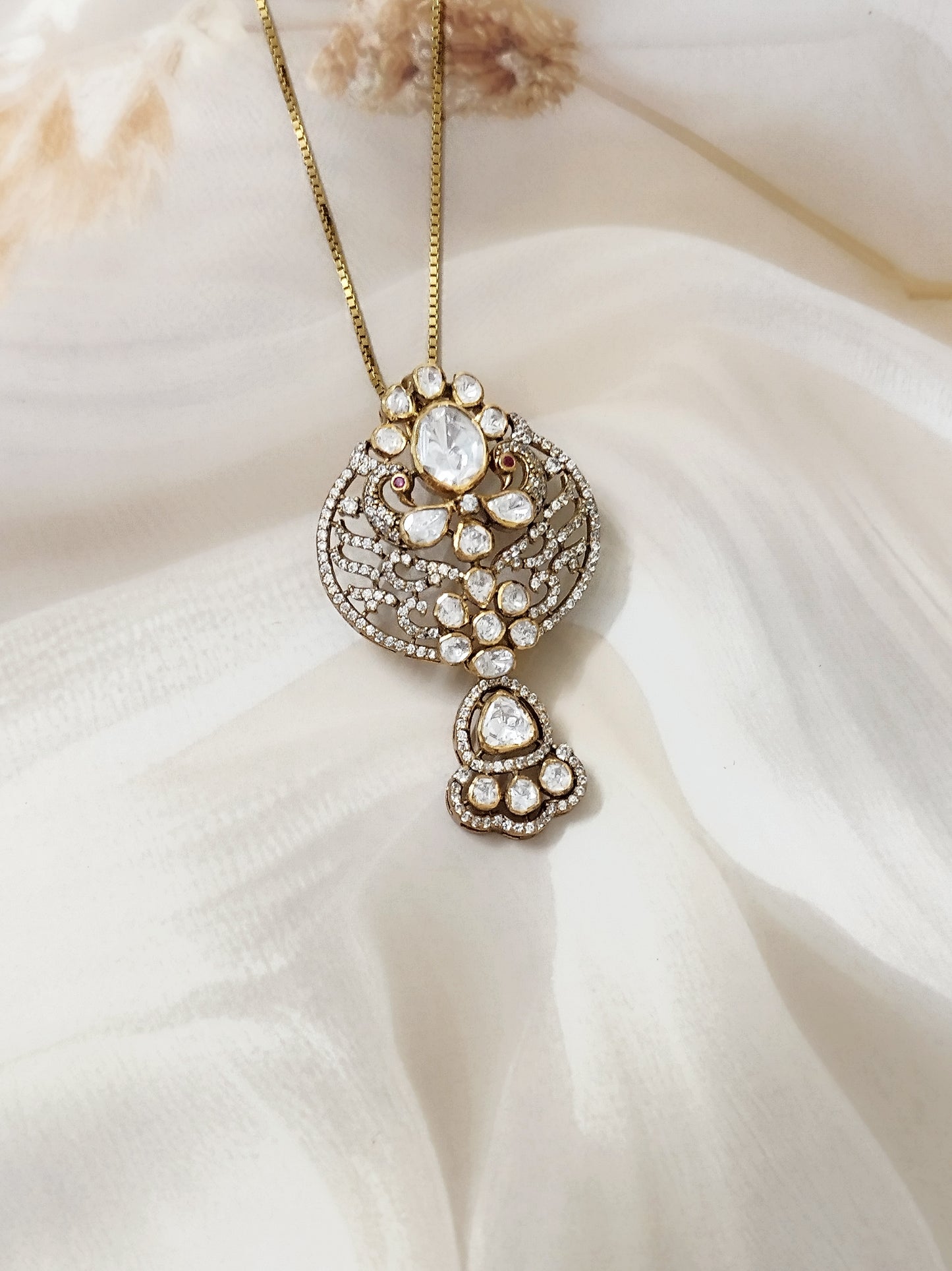 "Gold-plated polki Noor Classic Pendant with oval centerpiece and floral crystal design by Arka Jaipur", "Traditional kundan-style pendant with polki stones and ruby accents","Designer Indian pendant with floral motif and diamond-style detailing","Luxury heritage pendant handcrafted in Jaipur with polki and crystal work"