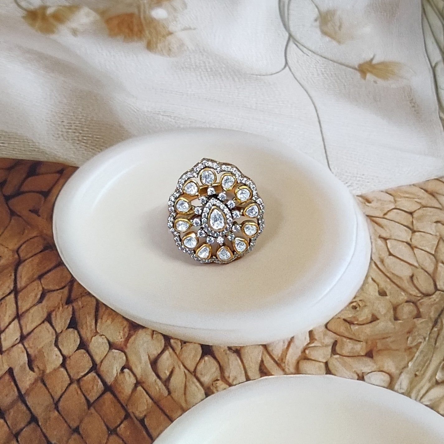 “Polki Blossom Ring by Arka Jaipur with uncut Polki stones in a floral design, teardrop centre stone, kundan-style detailing, and crystal halo photographed on a beige textured background.”