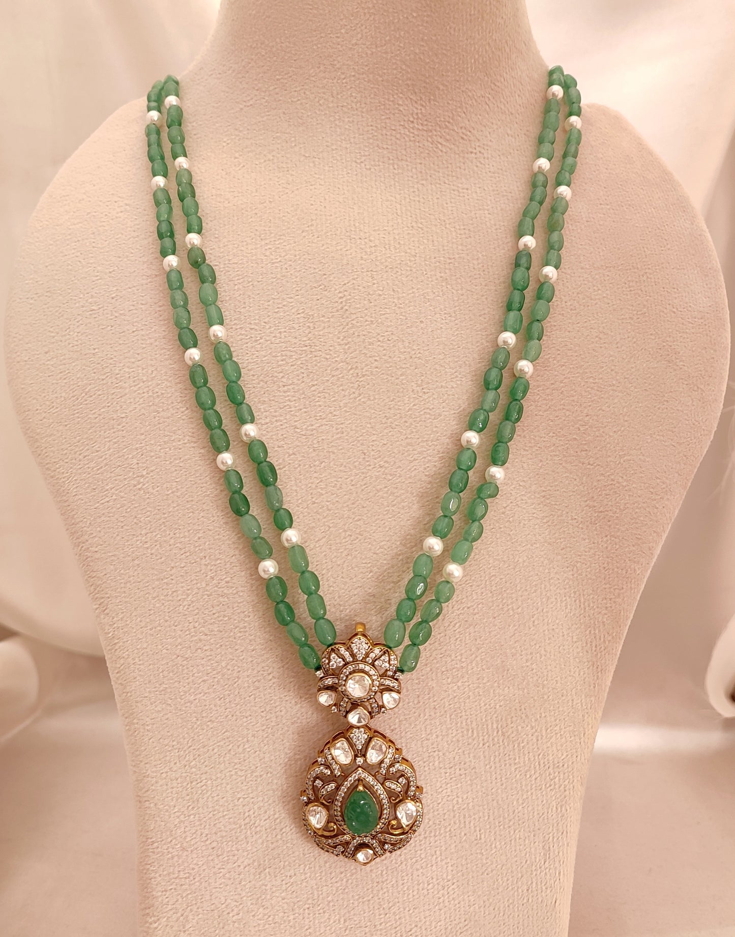 “Sanjh Emerald Pendant by Arka Jaipur featuring emerald-green stones, crystal accents, and intricate gold detailing in an elegant traditional jewellery design.”