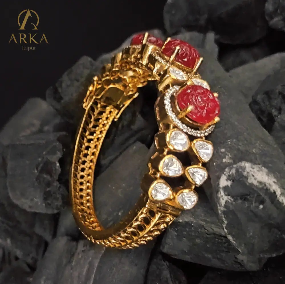 Celebrate royal artistry with the Ruby Majesty Bangle by Arka Jaipur. Handcrafted in gold-plated 925 silver, this exquisite design features carved ruby gemstones framed with uncut polki-style stones and delicate pavé detailing. A perfect heritage-inspired jewel that blends vibrant tradition with timeless elegance, ideal for weddings and festive occasions.