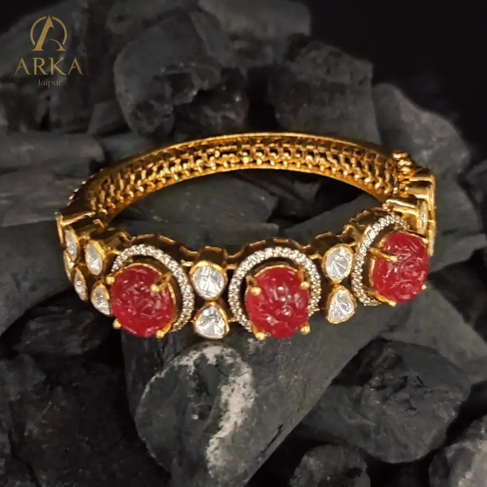 Celebrate royal artistry with the Ruby Majesty Bangle by Arka Jaipur. Handcrafted in gold-plated 925 silver, this exquisite design features carved ruby gemstones framed with uncut polki-style stones and delicate pavé detailing. A perfect heritage-inspired jewel that blends vibrant tradition with timeless elegance, ideal for weddings and festive occasions.