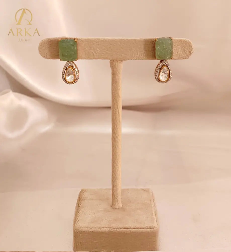 A regal blend of tradition and opulence, the Elysian Emerald Drops Earrings by Arka Jaipur feature intricately carved green stones paired with teardrop Polki drops, framed in shimmering CZ and sterling silver. A timeless statement for modern royalty.