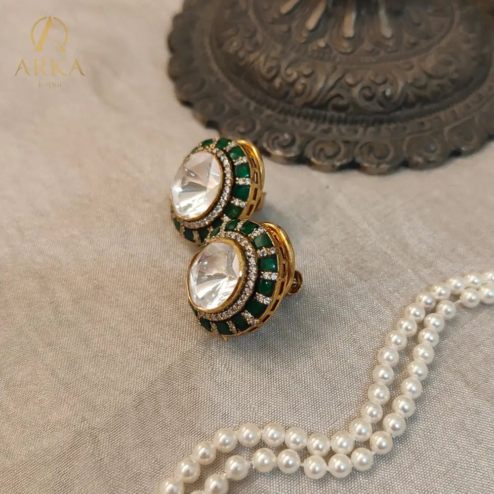 "Arka Jaipurs Eterna handcrafted Polki stud earrings with oval center stone, emerald-green halo, diamond accents, and gold-plated finish – heritage luxury jewelry."