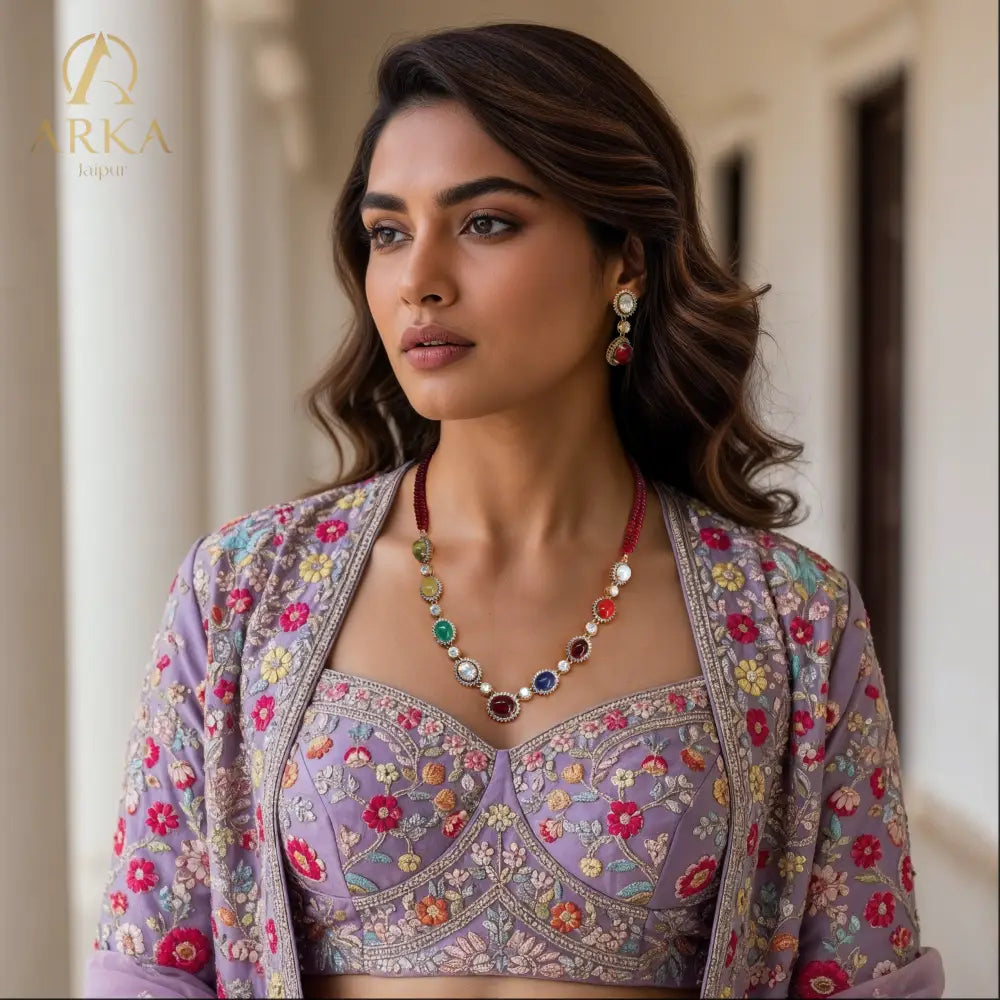 "Model wearing Navratna Radiance Set kundan necklace set by Arka Jaipur with nine colorful gemstones and matching earrings, styled with a floral embroidered lilac lehenga – traditional Indian jewelry"