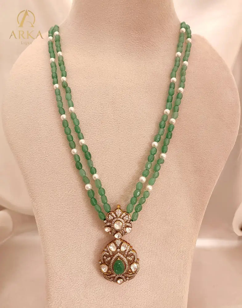 “Sanjh Emerald Pendant by Arka Jaipur featuring emerald-green stones, crystal accents, and intricate gold detailing in an elegant traditional jewellery design.”