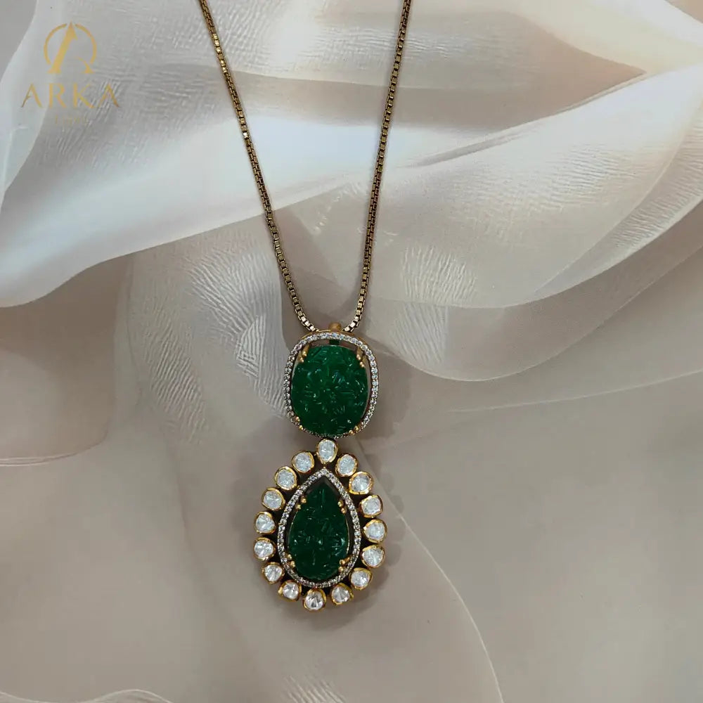 Experience timeless elegance with Arka Jaipur’s handcrafted Vintage Emerald Charm pendant, featuring intricately carved emerald-green stones in cushion and teardrop shapes. The pendant is adorned with a radiant halo of uncut Polki diamonds, set in gold plating for a regal heritage-inspired look. Perfect for weddings, festive celebrations, and luxury occasions, this statement pendant blends Mughal artistry with modern sophistication.