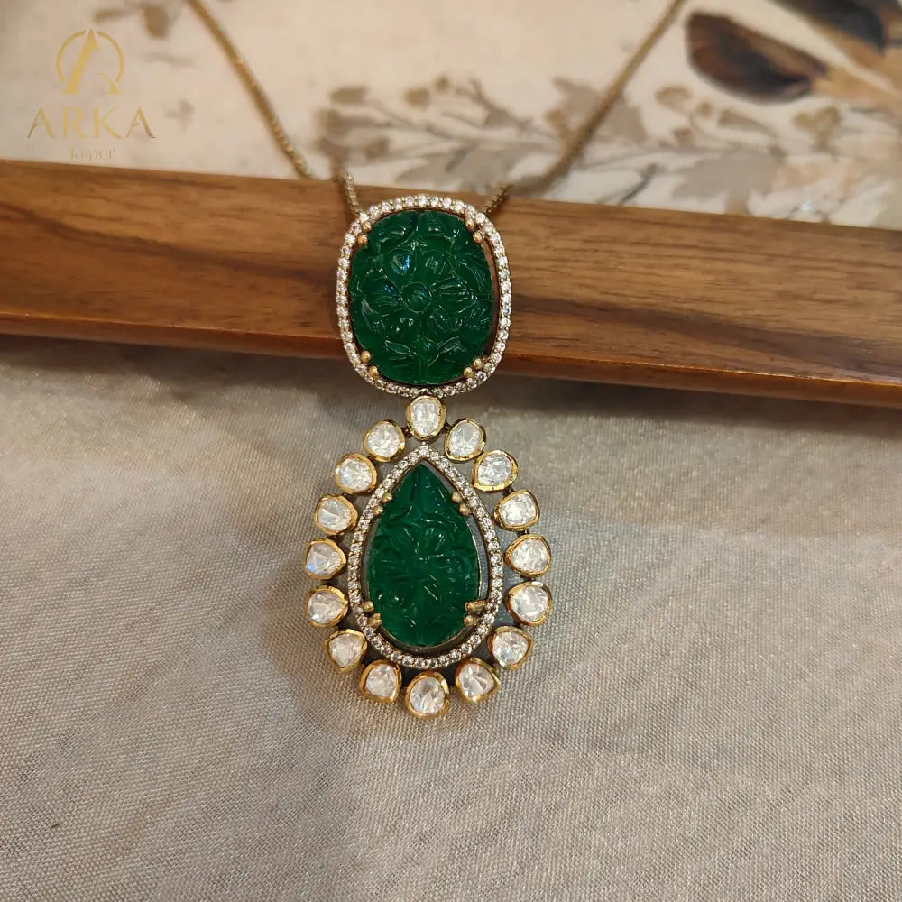 Experience timeless elegance with Arka Jaipur’s handcrafted Vintage Emerald Charm pendant, featuring intricately carved emerald-green stones in cushion and teardrop shapes. The pendant is adorned with a radiant halo of uncut Polki diamonds, set in gold plating for a regal heritage-inspired look. Perfect for weddings, festive celebrations, and luxury occasions, this statement pendant blends Mughal artistry with modern sophistication.