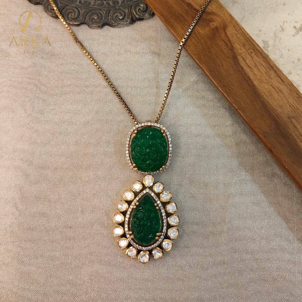 Experience timeless elegance with Arka Jaipur’s handcrafted Vintage Emerald Charm pendant, featuring intricately carved emerald-green stones in cushion and teardrop shapes. The pendant is adorned with a radiant halo of uncut Polki diamonds, set in gold plating for a regal heritage-inspired look. Perfect for weddings, festive celebrations, and luxury occasions, this statement pendant blends Mughal artistry with modern sophistication.