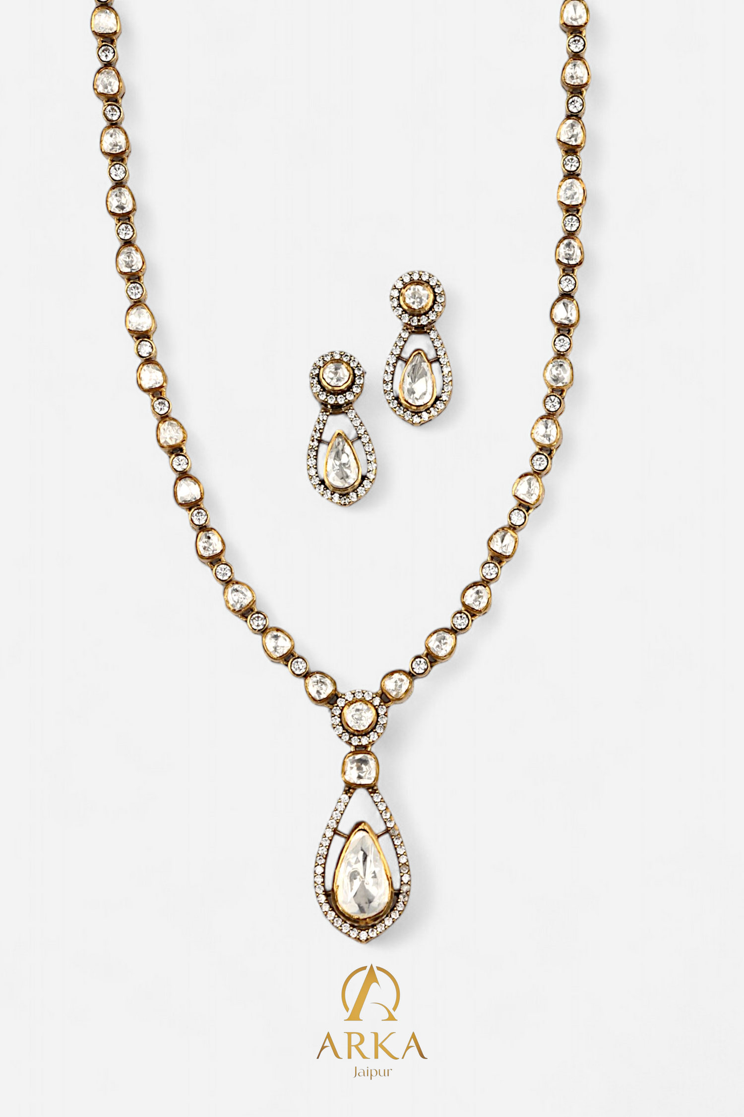 “Dewdrop Dream Set by Arka Jaipur featuring a gold-tone polki necklace with teardrop pendant and matching polki earrings on a white background.”