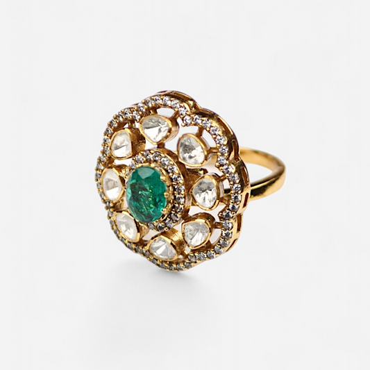 Inspired by divine femininity, the Hariti Ring by Arka Jaipur is a bold yet elegant statement piece. Crafted in radiant gold-tone finish, it features a central oval emerald framed by uncut Polki-style stones and a halo of fine crystals. This handcrafted ring evokes regal charm and traditional craftsmanship, perfect for festive, bridal, or high-fashion occasions.