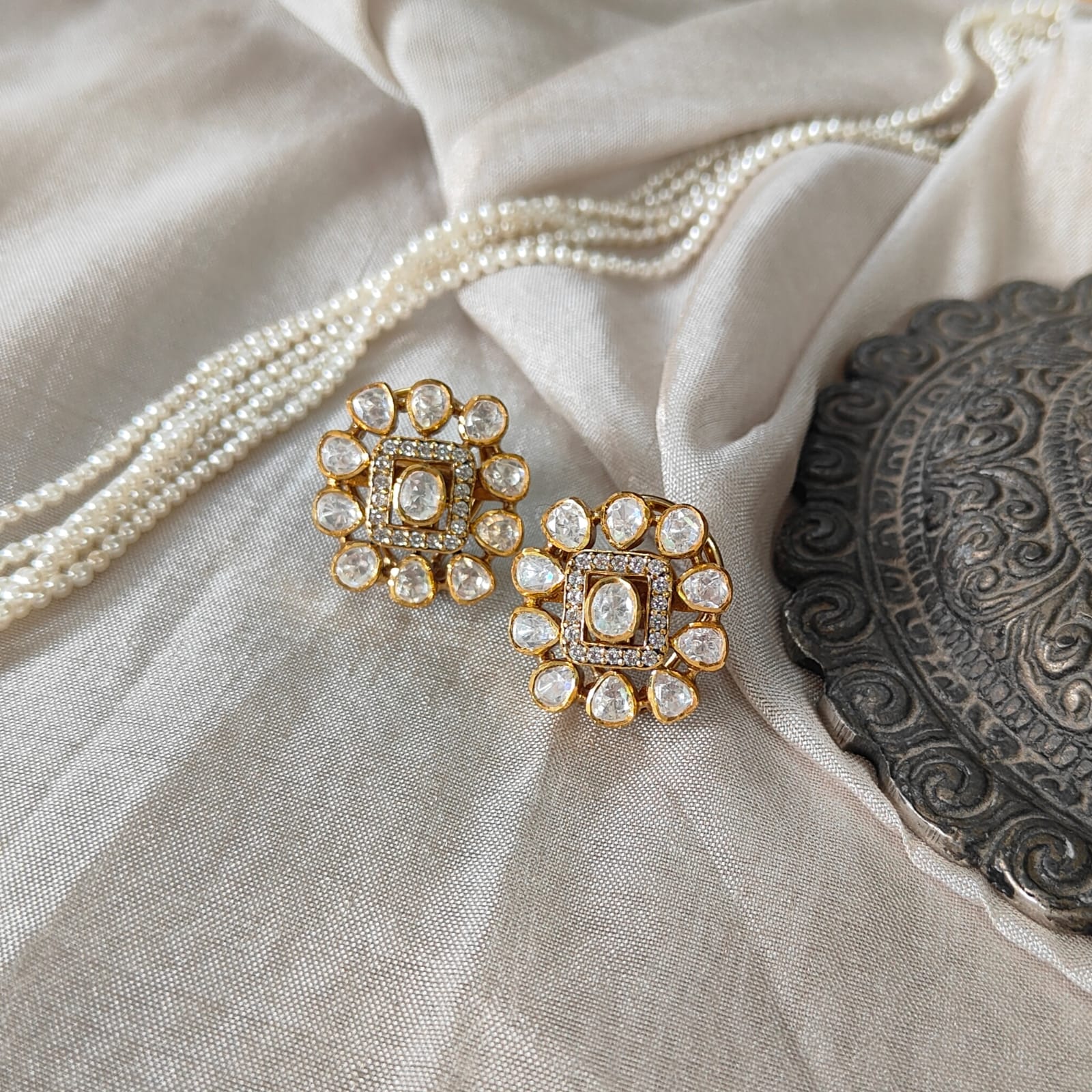 Ivory Halo Studs with square polki center and halo design in a luxury flatlay
