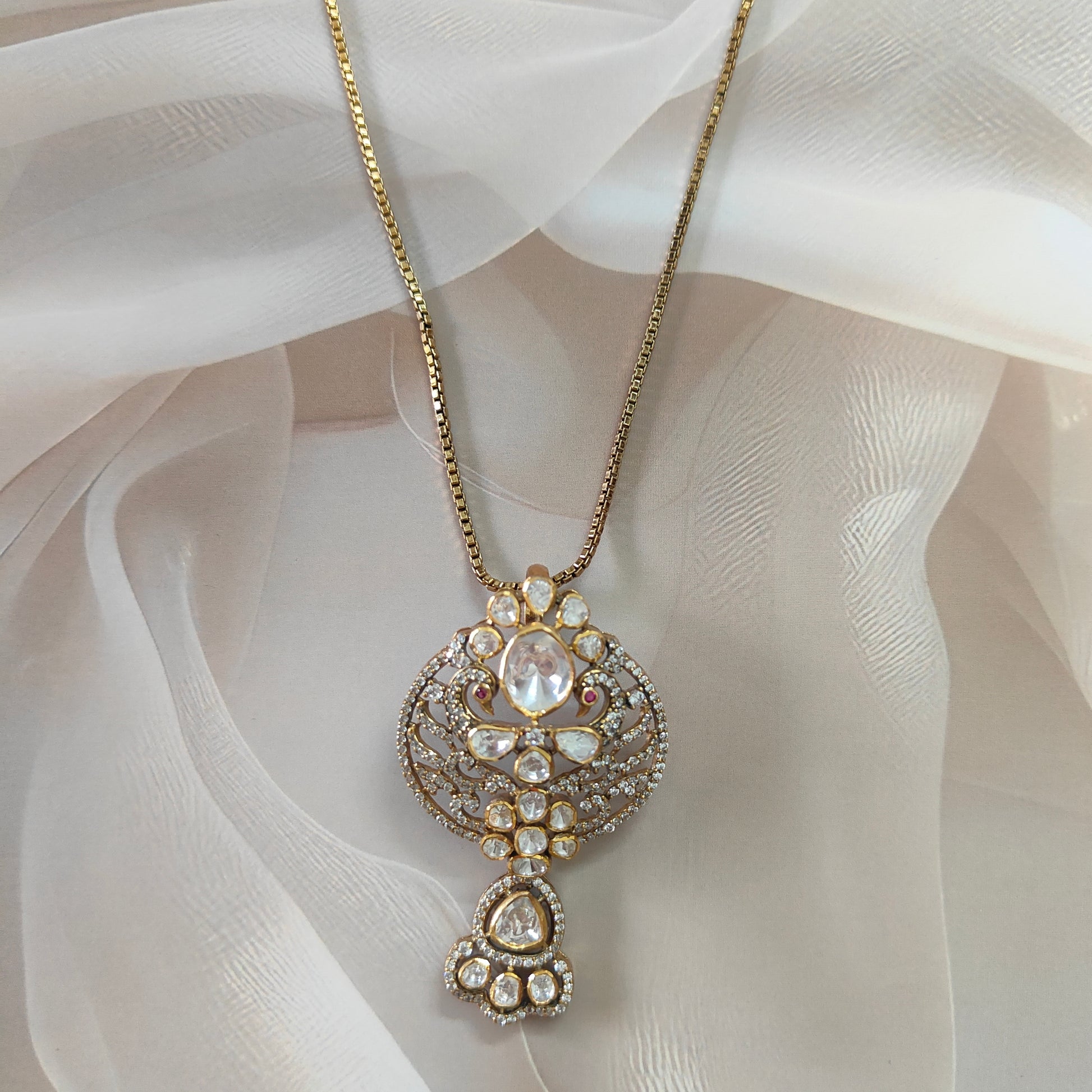 "Gold-plated polki Noor Classic Pendant with oval centerpiece and floral crystal design by Arka Jaipur", "Traditional kundan-style pendant with polki stones and ruby accents","Designer Indian pendant with floral motif and diamond-style detailing","Luxury heritage pendant handcrafted in Jaipur with polki and crystal work"