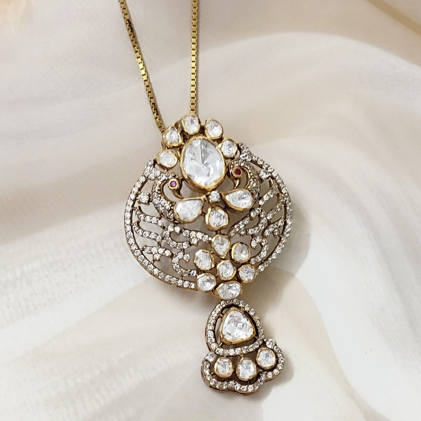 "Gold-plated polki Noor Classic Pendant with oval centerpiece and floral crystal design by Arka Jaipur", "Traditional kundan-style pendant with polki stones and ruby accents","Designer Indian pendant with floral motif and diamond-style detailing","Luxury heritage pendant handcrafted in Jaipur with polki and crystal work"