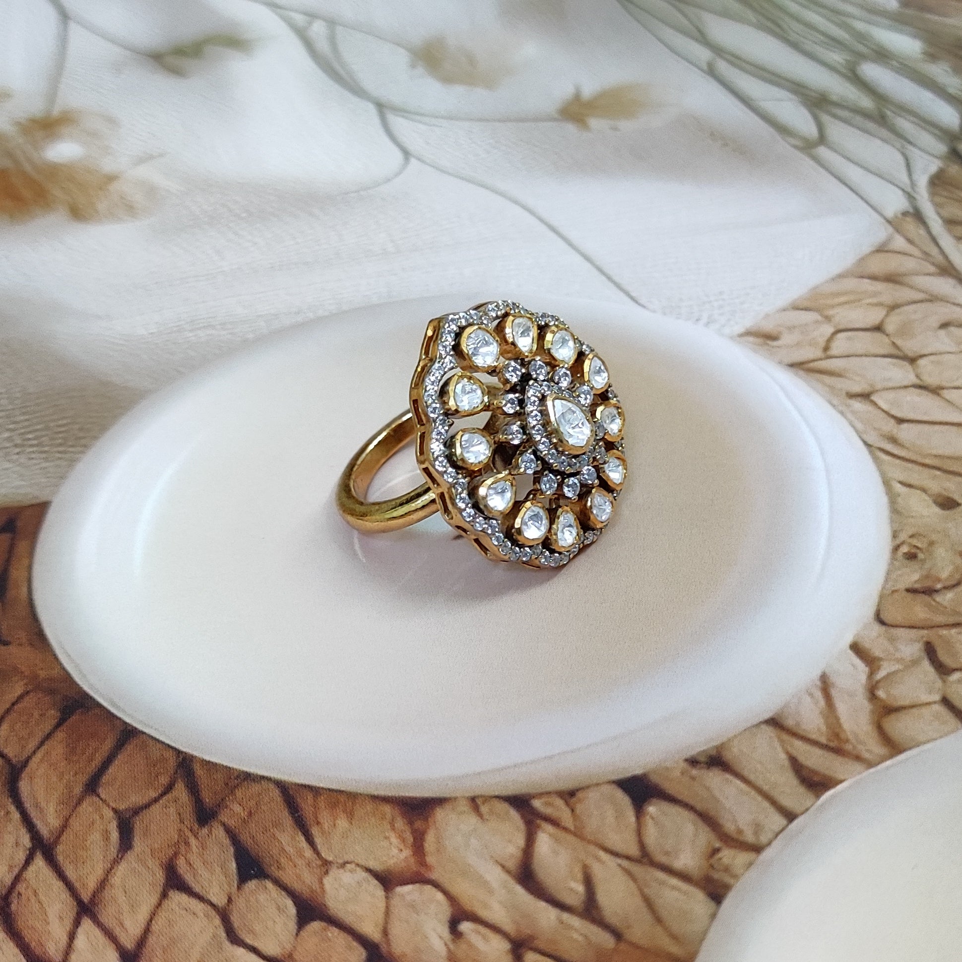 “Polki Blossom Ring by Arka Jaipur with uncut Polki stones in a floral design, teardrop centre stone, kundan-style detailing, and crystal halo photographed on a beige textured background.”