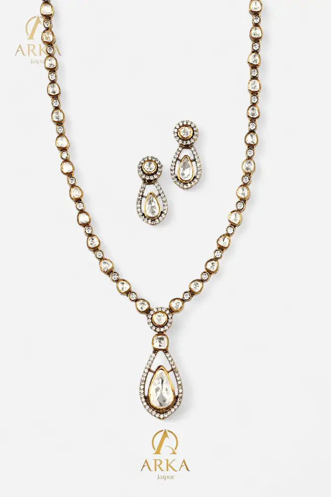 “Dewdrop Dream Set by Arka Jaipur featuring a gold-tone polki necklace with teardrop pendant and matching polki earrings on a white background.”