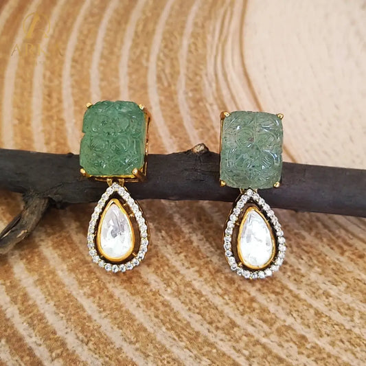 A regal blend of tradition and opulence, the Elysian Emerald Drops Earrings by Arka Jaipur feature intricately carved green stones paired with teardrop Polki drops, framed in shimmering CZ and sterling silver. A timeless statement for modern royalty.