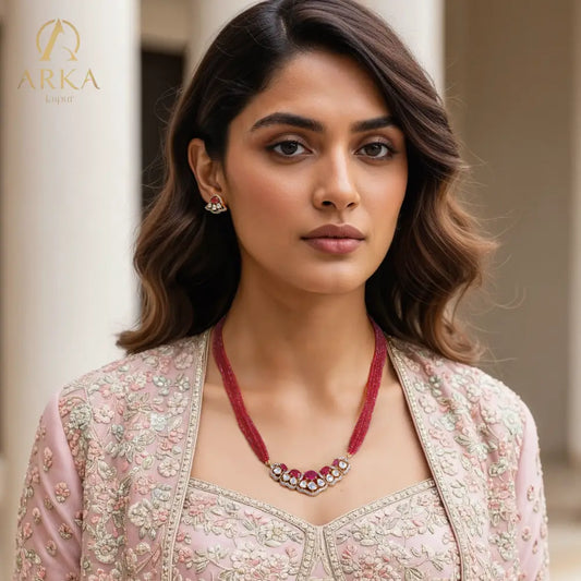 “Scarlet Mist Set by Arka Jaipur – modern chic designer pendant & stud earrings with oval ruby centerpiece, teardrop white stones, gold finish, and diamond outline.”