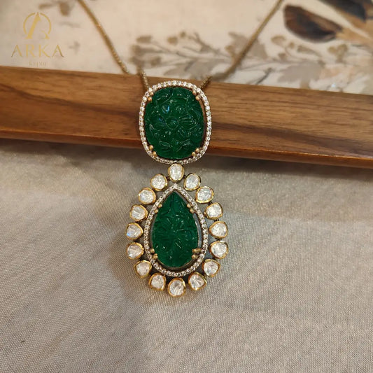 Experience timeless elegance with Arka Jaipur’s handcrafted Vintage Emerald Charm pendant, featuring intricately carved emerald-green stones in cushion and teardrop shapes. The pendant is adorned with a radiant halo of uncut Polki diamonds, set in gold plating for a regal heritage-inspired look. Perfect for weddings, festive celebrations, and luxury occasions, this statement pendant blends Mughal artistry with modern sophistication.
